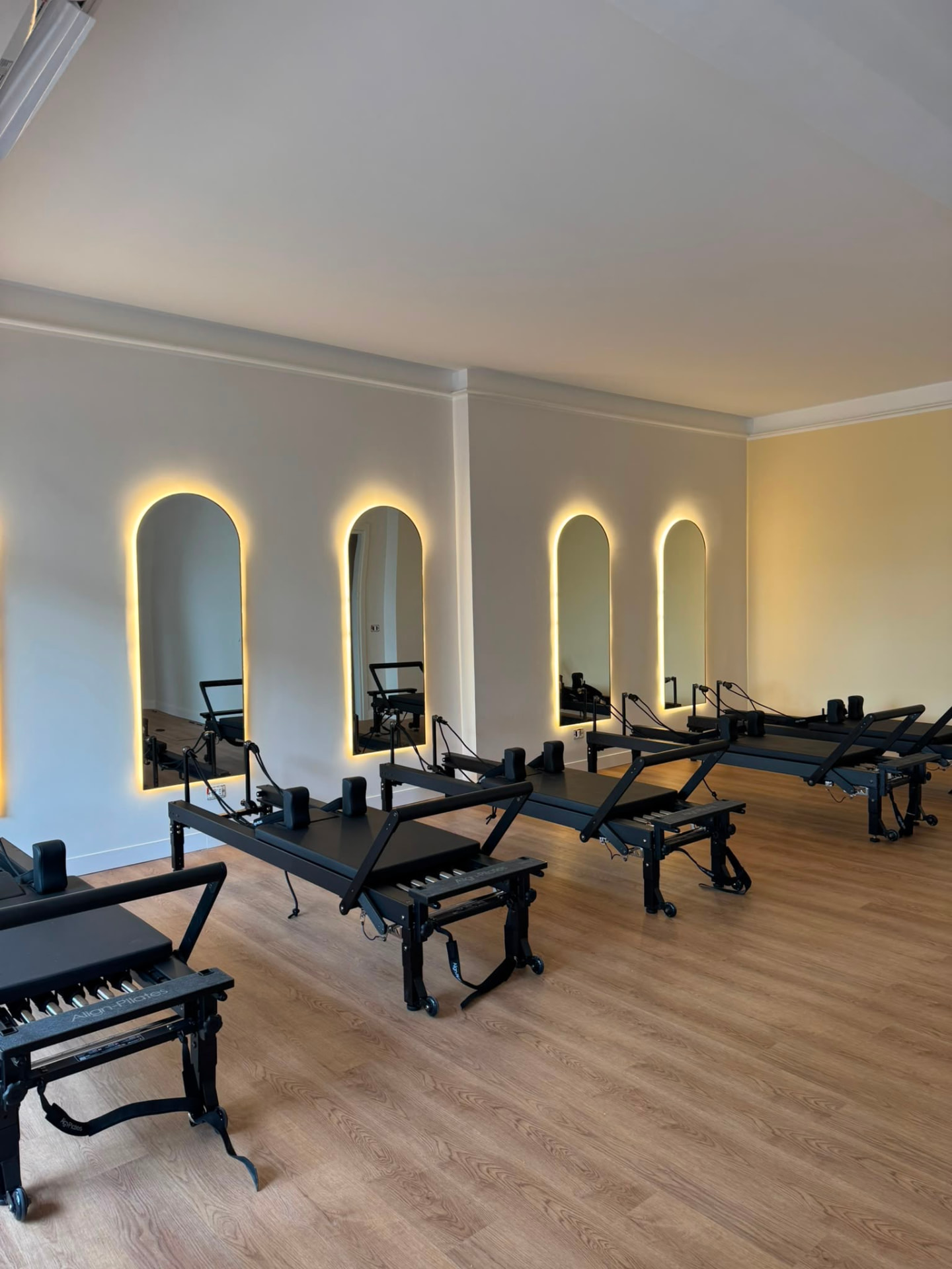 Sala principale di Leveza Pilates Studio con Reformer C8 Pro Align-Pilates neri e specchi ad arco retroilluminati